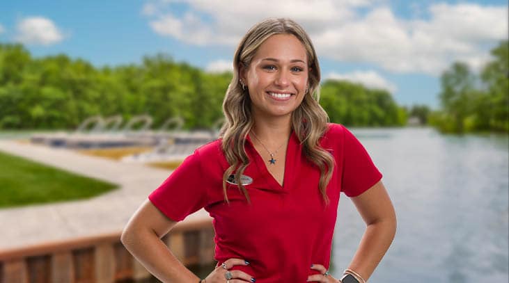 Cove Seasonal team member smiling in a red polo in front of Oneida lake